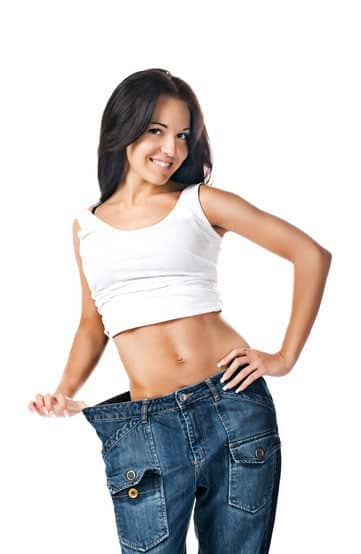 Woman demonstrating weight loss by wearing an old pair of jeans.
