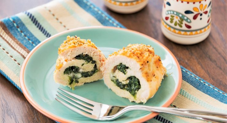 A baked chicken breast is stuffed with spinach and cheese and rolled in bread crumbs.